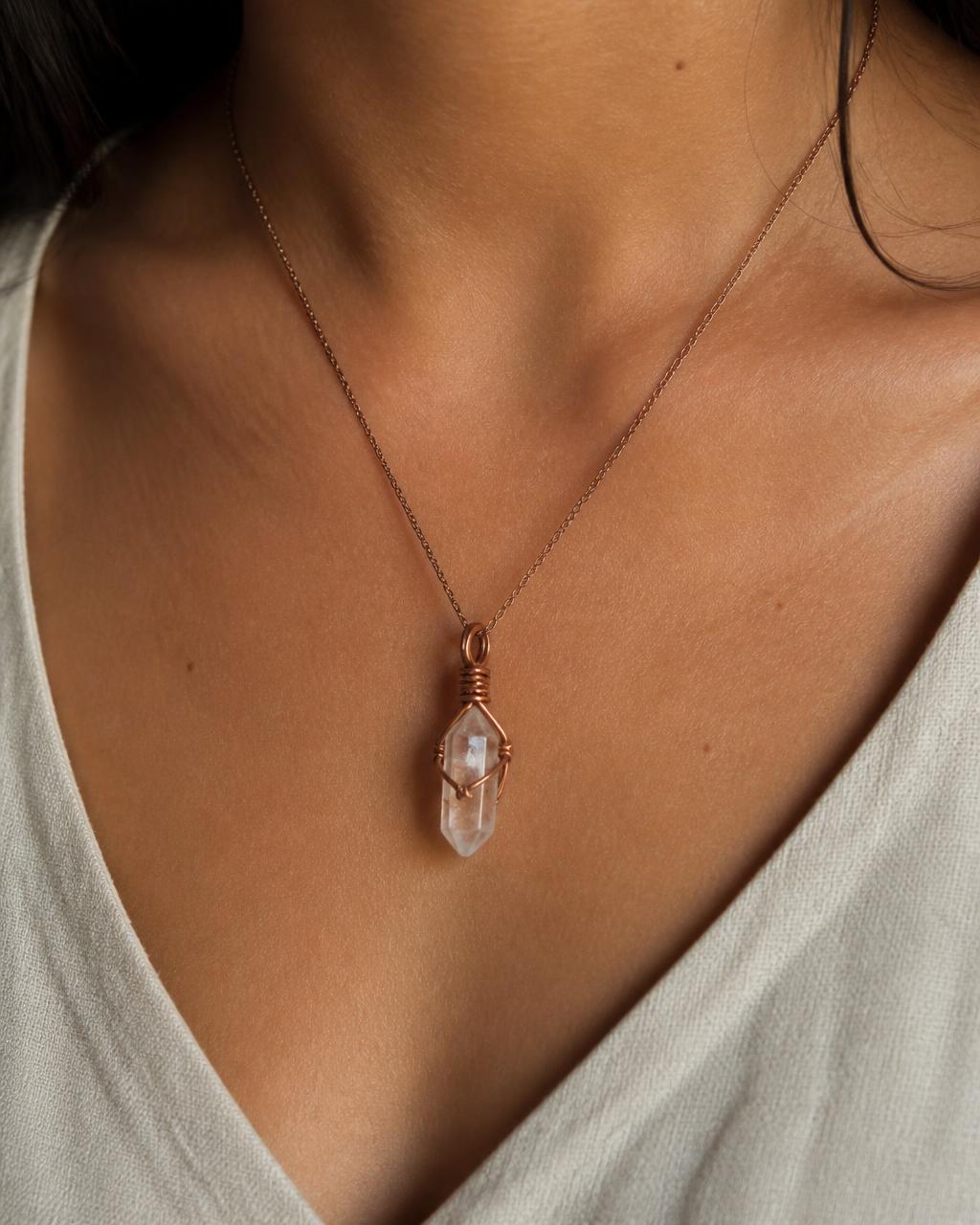 A woman wearing a copper wire-wrapped quartz pendant on a fine chain